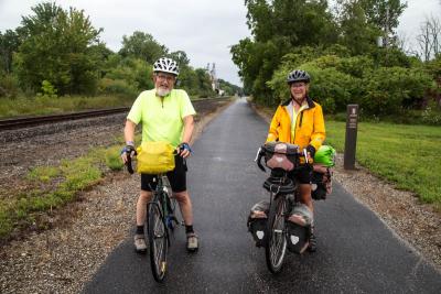 two cyclists on paved trail stopping for a photo