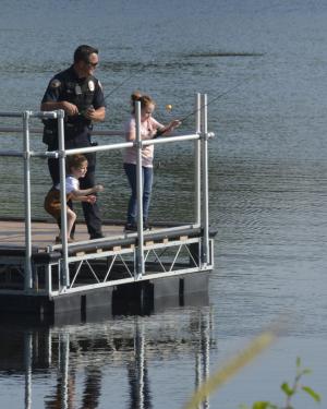 Officer and two young girls fishing on pier at Trail Lake Park