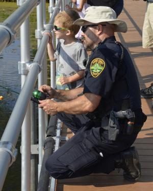 Officer and young boy looking at the water and fishing from fishing pier 