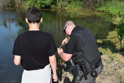 Officer helping boy take fish off a hook