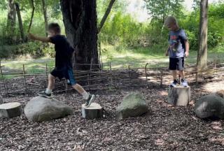 two children balance on logs and stumps