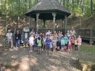 A group of kids poses with an owl mascot to receive their junior ranger badges. 