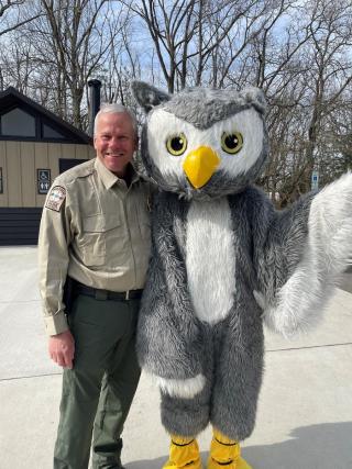 a park ranger poses with a fluffy owl mascot