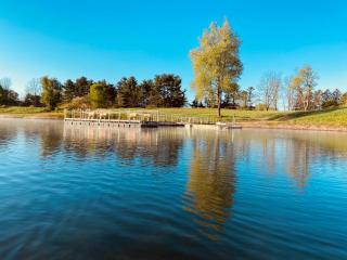 View from the lake of fishing dock and spring green shoreline with blue sky overhead.