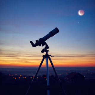 telescope aimed at moon in front of sunset
