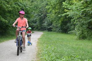 two cyclists on limestone paved Headwaters Trail surrounded by green grass and trees