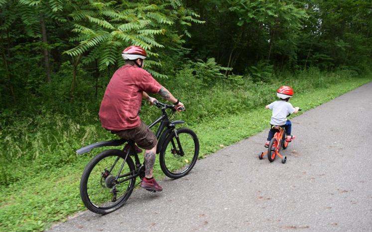 man and child riding bikes on path 
